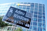 photo d'une pancarte avec le texte Adieu windows bonjour le libre devant l'immeuble vitré de Microsoft